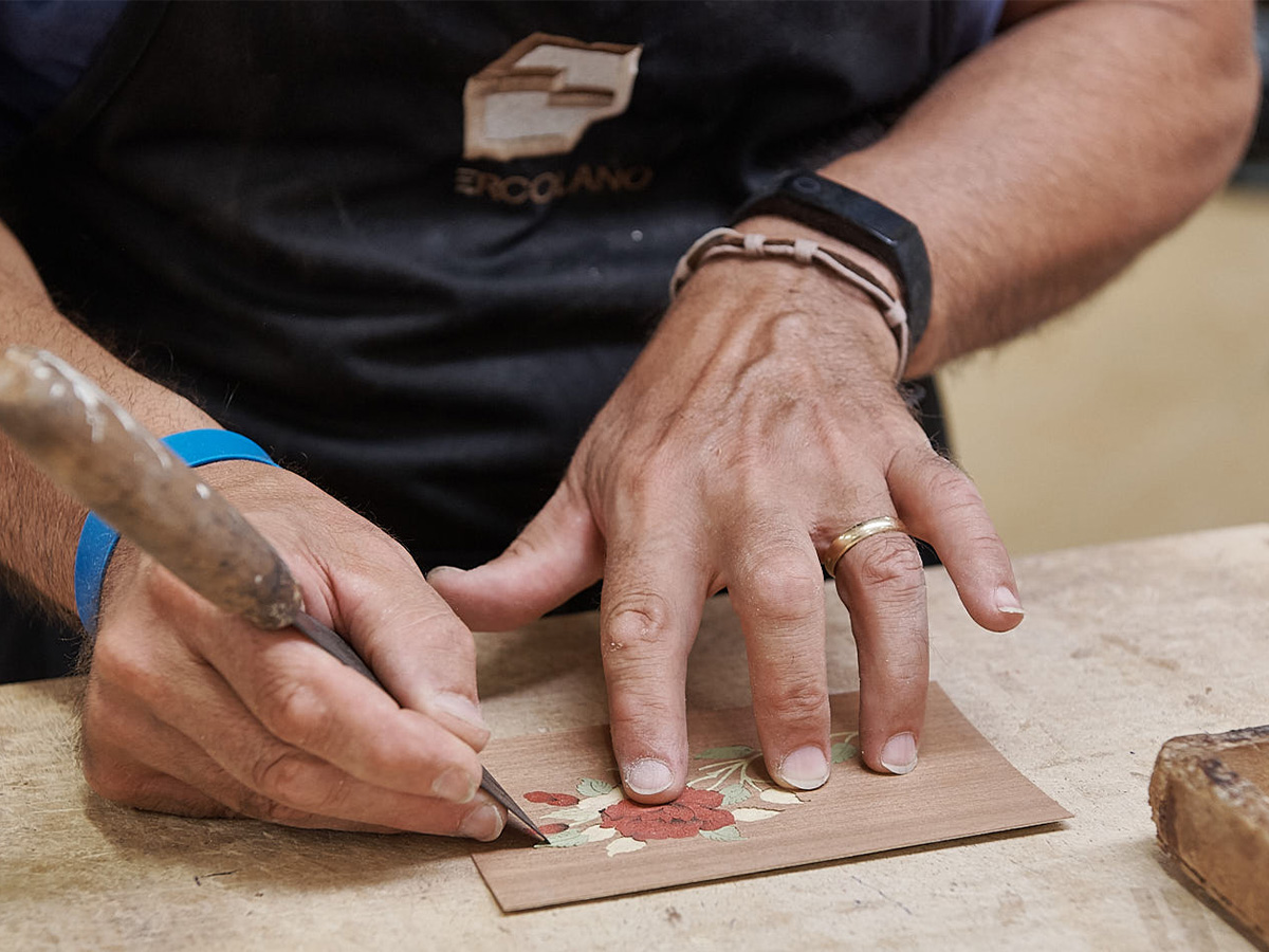Craftsman hand-cutting a floral marquetry inlay for an Ercolano Inlaid music box